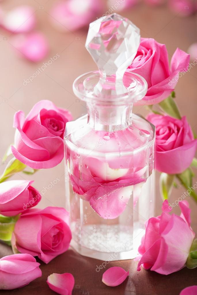 Perfume bottle and pink rose flowers. spa aromatherapy Stock Photo by