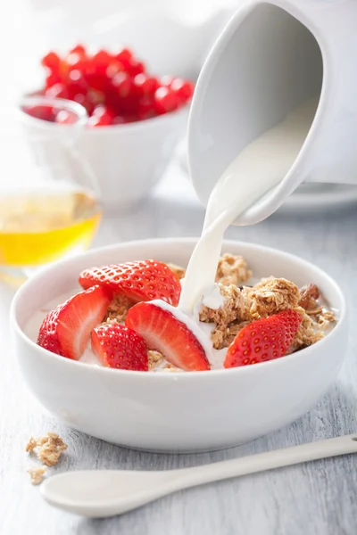 Milch über Müsli mit Erdbeere zum Frühstück gießen — Stockfoto