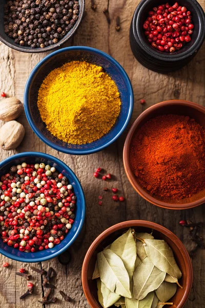 Spices in bowls: pink black pepper, paprika powder, curry, bay l — Stock Photo, Image