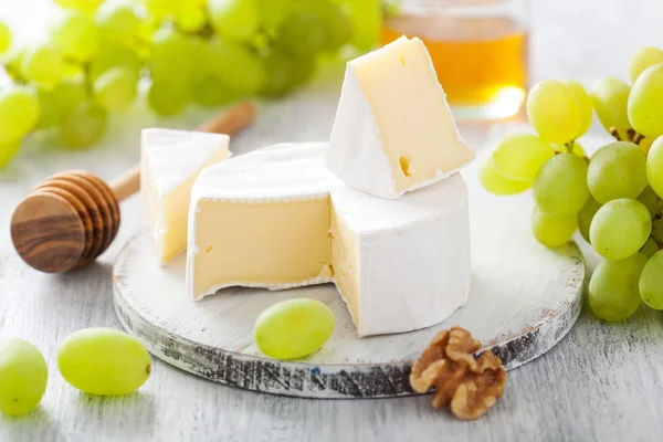 Camembert ost med druvor, honung och nötter på trä bak — Stockfoto