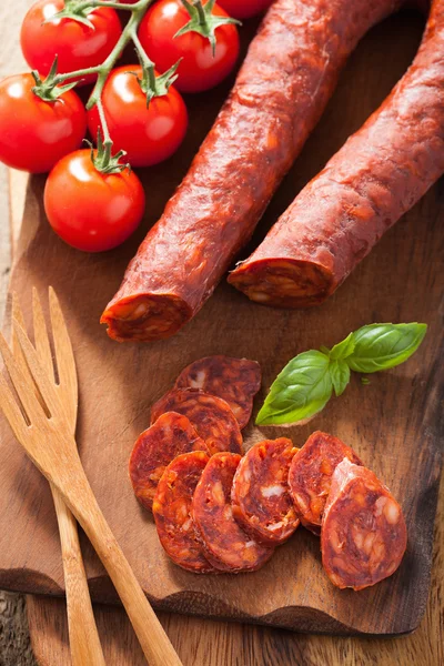 Spanish chorizo sausage with basil on chopping board — Stock Photo, Image