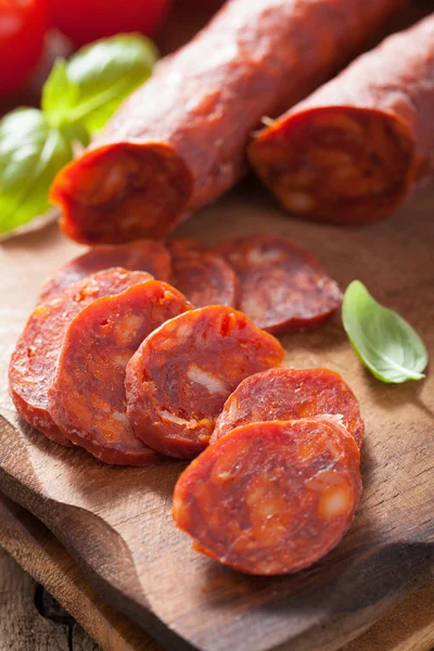 Spanish chorizo sausage with basil on chopping board — Stock Photo, Image