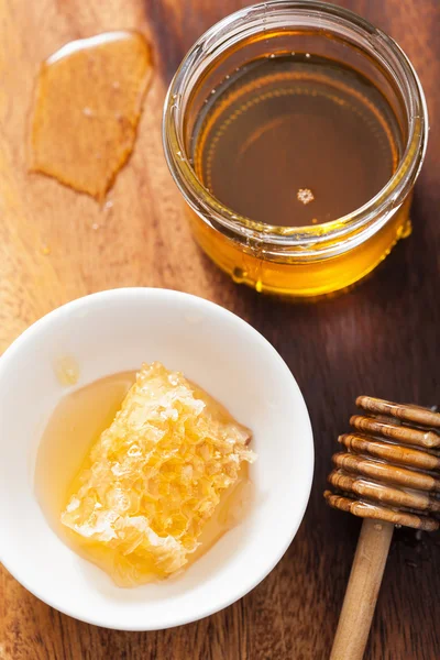 Wabenlöffel und Honig im Glas auf Holzgrund — Stockfoto
