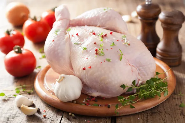 Poulet cru entier au poivre de rose et thym Photo De Stock