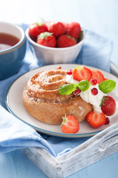 Söta kanelbulle med grädde och jordgubbar till frukost — Stockfoto