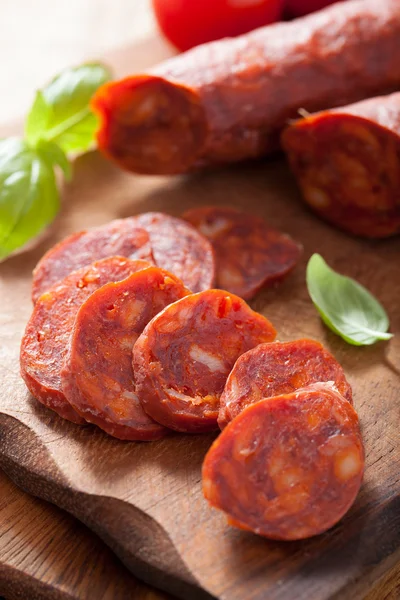 Salchicha de chorizo español con albahaca en tabla de cortar Imagen de stock