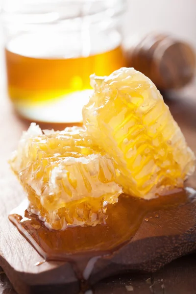 Favo de mel dipper e mel em jarra no fundo de madeira — Fotografia de Stock
