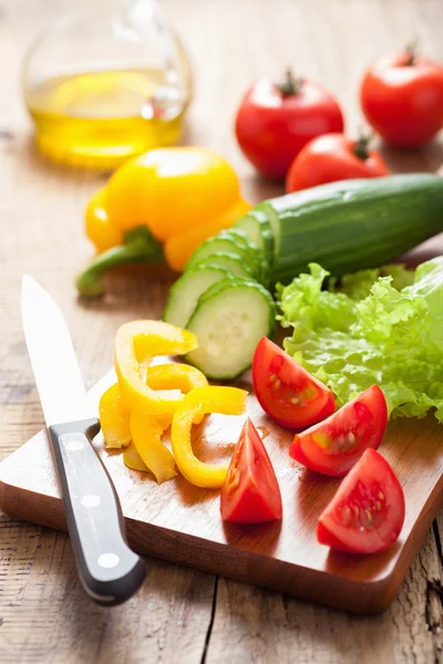 Chopping fresh vegetables cucumber tomatoes pepper and salad lea — Stock Photo, Image