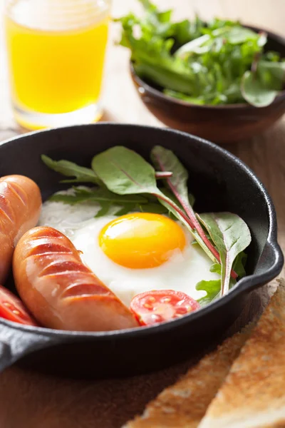 Fried egg sausages tomatoes in pan for breakfast — Stock Photo, Image