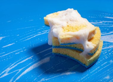 Sünger temizleme köpük sabun köpüğü mavi arka planda, ev yıkama konsepti