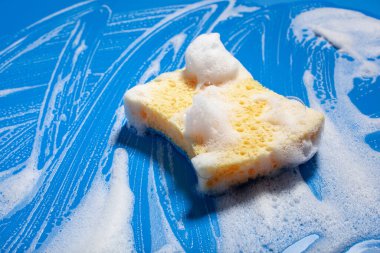 Sünger temizleme köpük sabun köpüğü mavi arka planda, ev yıkama konsepti