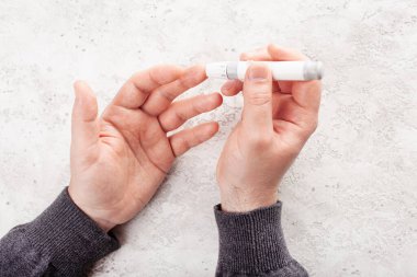 Erkek elleri kan şekeri ve keton seviyelerini glikoz ölçmek için parmak üstüne mızrak kullanır. İlaç diyabeti keto diyet sağlık hizmetleri evde