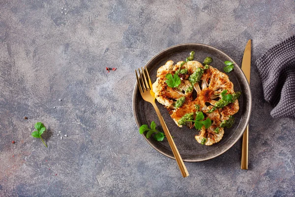 cauliflower steaks with herb sauce and spice. plant based meat substitute