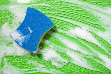 Sünger temizleme köpük sabun köpüğü yeşil arka planda, ev yıkama konsepti