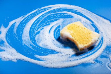 Sünger temizleme köpük sabun köpüğü mavi arka planda, ev yıkama konsepti