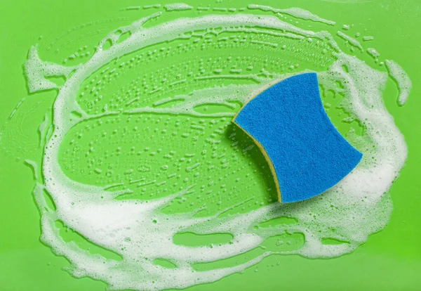 スポンジの拭き取り泡石鹸は緑の背景に 家庭用洗濯の概念を吸う — ストック写真