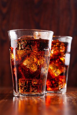 Bir bardak soğuk kola, ahşap zemin üzerinde buz.