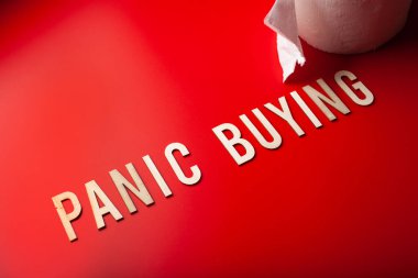 Panik halinde tuvalet kağıdı alıyor. Kırmızı arka planda tahta harf yazıyor.