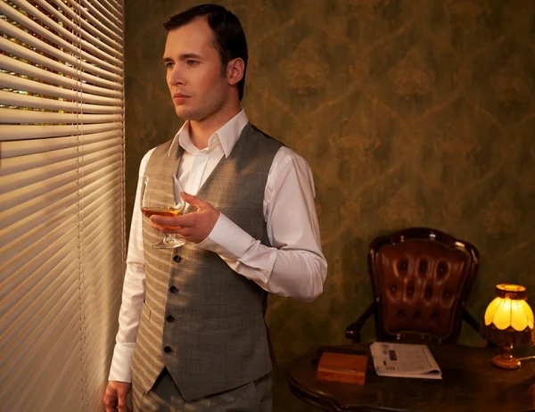 Homme rétro avec un verre debout près de la fenêtre — Photo