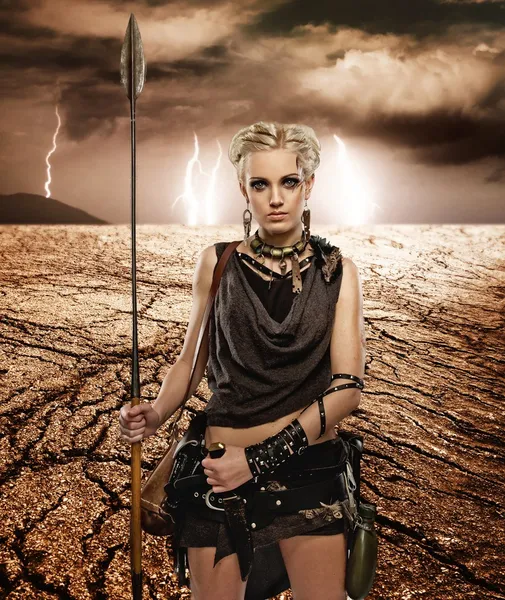 Woman with a spear in a desert — Stock Photo, Image