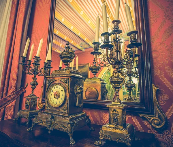 Antique clock and chandelier against mirror — Stock Photo, Image