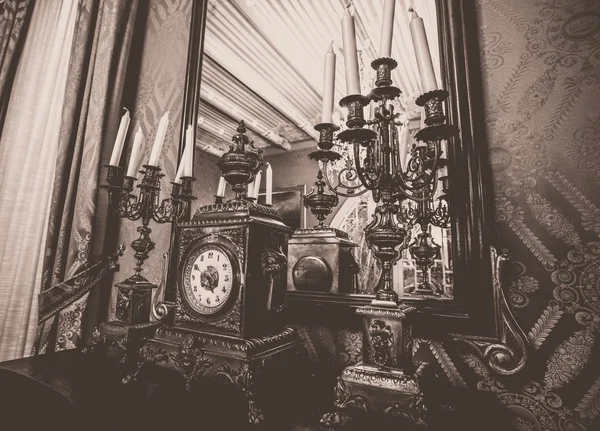 Antique clock and chandelier against mirror — Stock Photo, Image