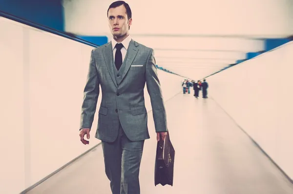 Uomo in classico abito grigio con valigetta passeggiando per il corridoio — Foto Stock
