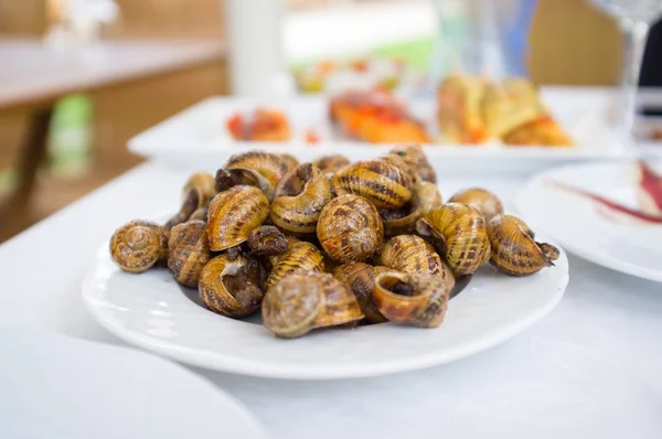 Plaat op tafel vol met gebakken slakken — Stockfoto