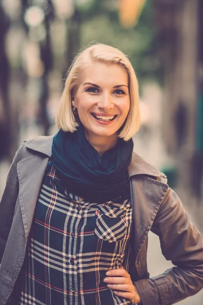 Schöne lachende blonde Frau mit blauem Schal im Freien — Stockfoto