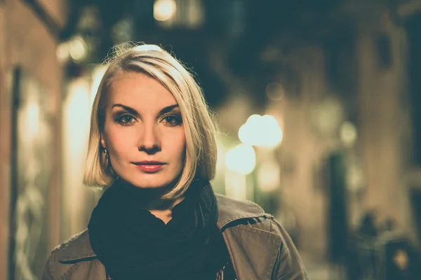 Piękne blond kobieta w płaszcz na zewnątrz w nocy — Zdjęcie stockowe