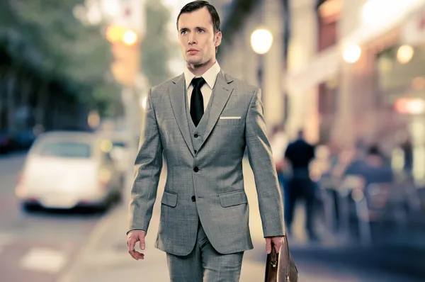 Hombre en traje gris clásico con maletín caminando al aire libre — Foto de Stock