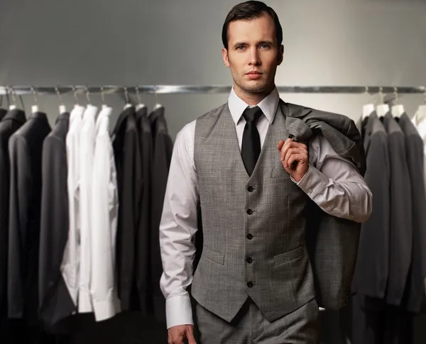 Zakenman in klassieke vest tegen rij van kostuums in winkel — Stockfoto