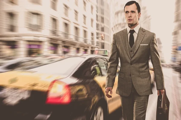 Hombre en traje gris clásico con maletín caminando al aire libre — Foto de Stock