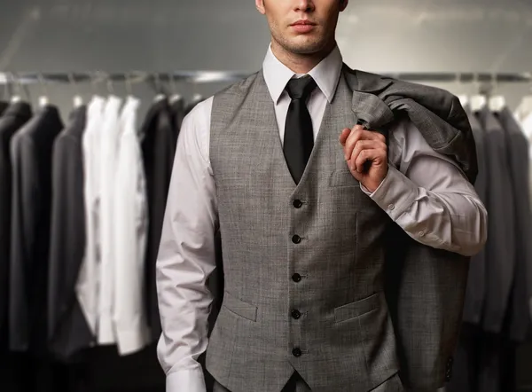 Businessman in classic vest against row of suits in shop — Stock Photo, Image