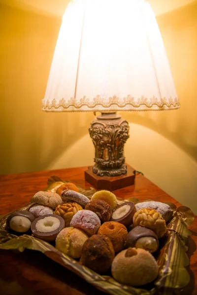 Různé sladkosti na desce poblíž lampa — Stock fotografie