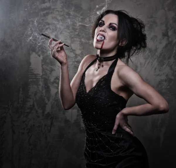 Женщина-вампир в черном платье курит — стоковое фото