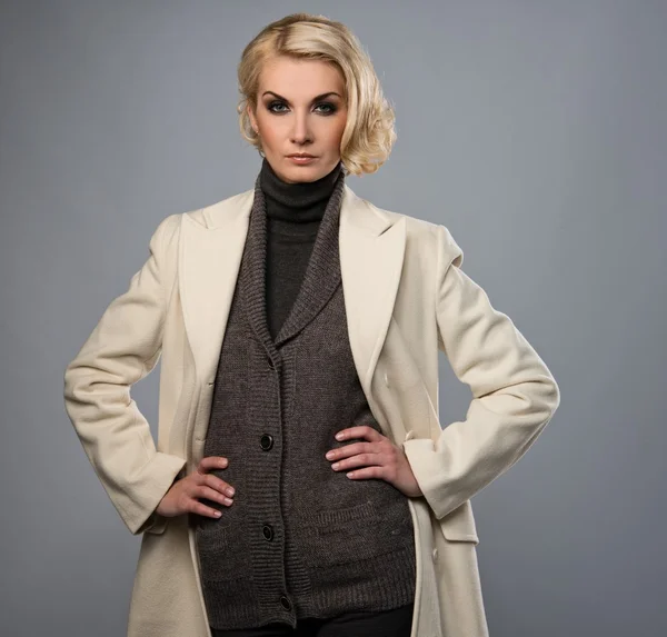 Elegante Frau im weißen Mantel isoliert auf grau — Stockfoto