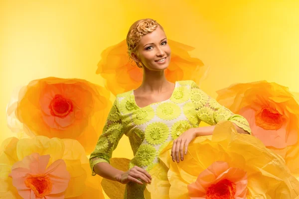 Jovem mulher entre grandes flores amarelas — Fotografia de Stock