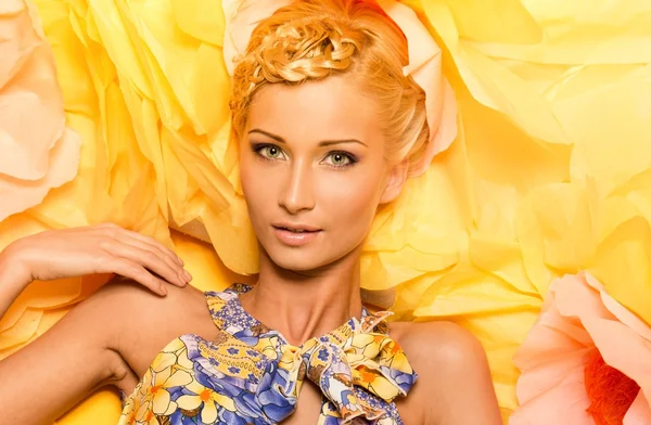 Mladá žena mezi velké žluté květy — Stock fotografie