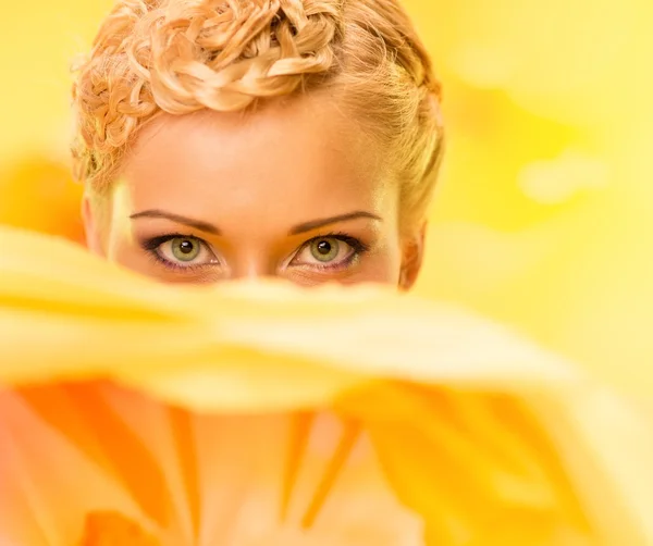 Jovem mulher entre grandes flores amarelas — Fotografia de Stock