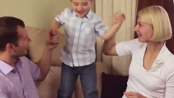 Ouders spelen met babyjongen springen op een sofa — Stockvideo
