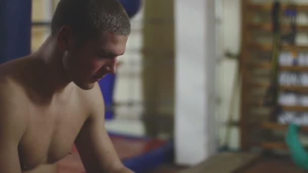 Young boxer wrapping bandages on his hand before fight — Stock Video