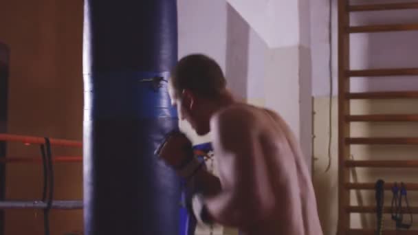 Молодой боксёр тренируется на боксерской груше — стоковое видео