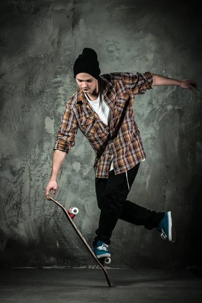 Jonge man in hoed en shirt stunt uitvoeren op skateboard — Stockfoto