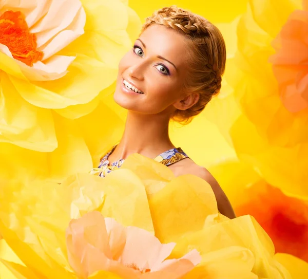 Vackra unga glada blonda kvinnan i färgglada klänning bland stora gula blommor — Stockfoto