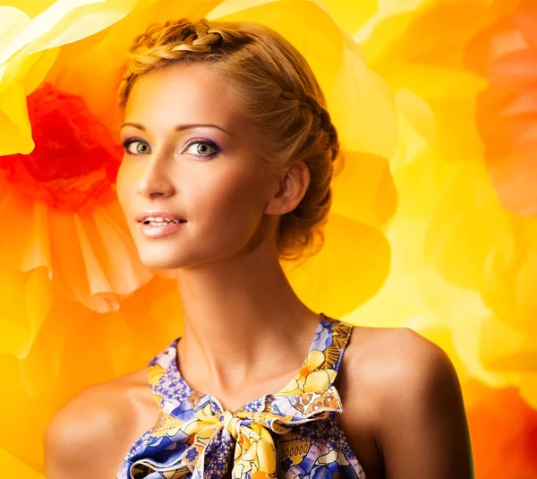 Mulher loira jovem bonita em vestido colorido entre grandes flores amarelas — Fotografia de Stock