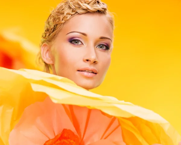 Veselá blonďatá krasavice v barevných šatech mezi velké žluté květy — Stock fotografie