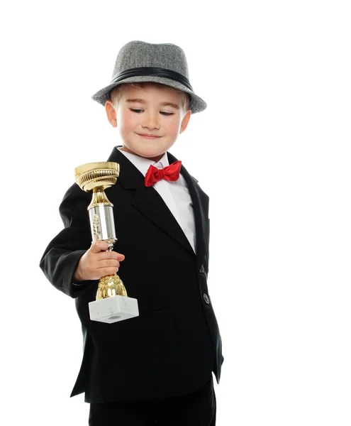 Niño feliz en traje negro sosteniendo la taza de premio — Foto de Stock