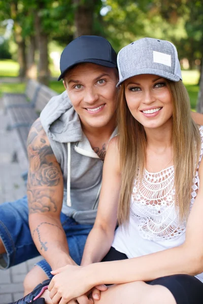 Jovem feliz sorrindo casal desportivo sentado no banco em um parque — Fotografia de Stock