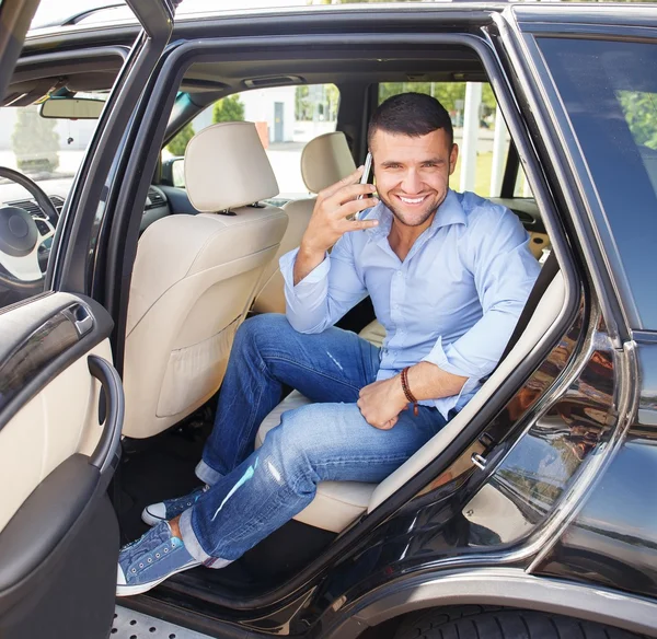 Hombre guapo y elegante en un asiento trasero con un teléfono móvil —  Fotos de Stock